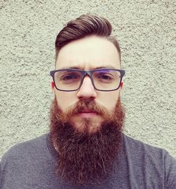 Portrait of young man wearing eyeglasses against wall