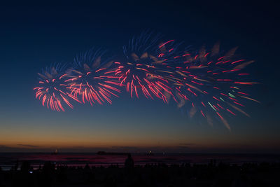 Low angle view of firework display over landscape at night