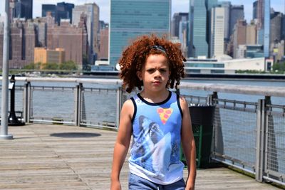 Portrait of boy walking by railing in city