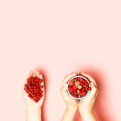 Female hands with assorted raspberries and strawberries on a pink background. flat lay. top view