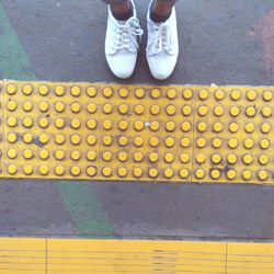 Low section of person standing on yellow road