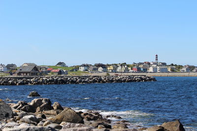 Sea by buildings against clear blue sky