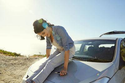 Happy young woman sitting on a car