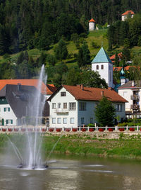 Fountain in lake against buildings