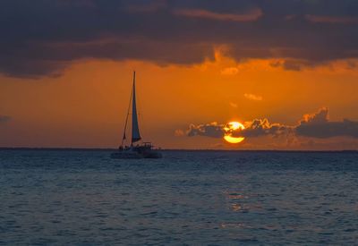 Sailboat sailing on sea against sky during sunset