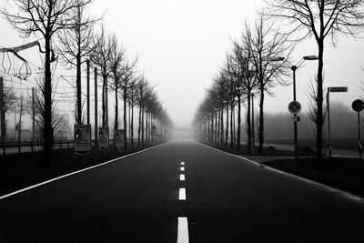 Road amidst bare trees against clear sky