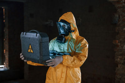Rear view of man wearing hat standing against wall