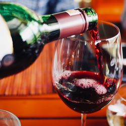 Close-up of bottle pouring red wine in glass on table