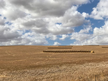 Hay bales on field against sky