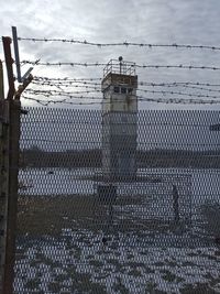 Fence by building against sky during winter