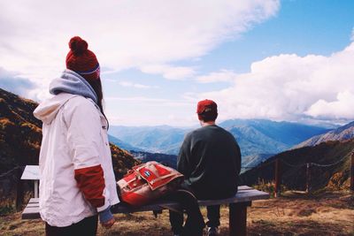 Rear view of men sitting on landscape against mountain