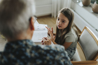 Girl doing homework with grandfather at home