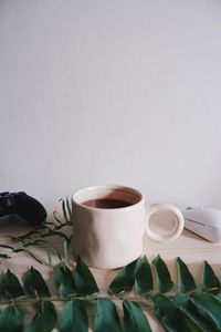 Close-up of coffee cup on table against wall