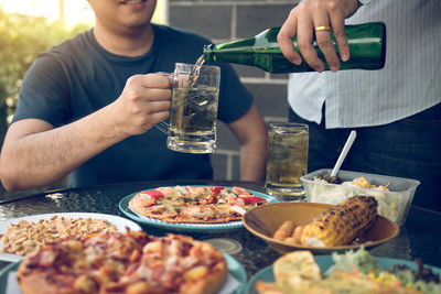 Midsection of man holding ice cream on table in restaurant