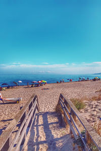 People at beach against blue sky