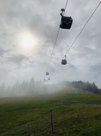 Overhead cable car on field against sky