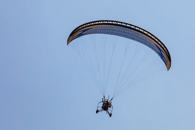 Low angle view of person paragliding against clear sky