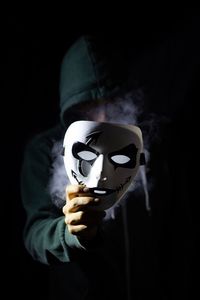 Man holding mask against black background
