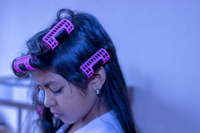 Close-up of girl with hair curlers at home