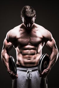 Shirtless muscular man exercising against black background