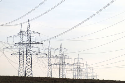 Low angle view of electricity pylon on land against sky