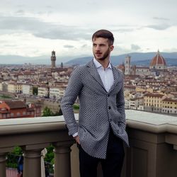 Young man standing in city against sky