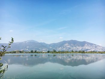 Scenic view of lake and mountains against clear blue sky