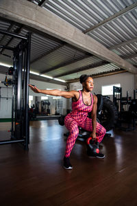 Determined woman doing squat exercises with kettlebell. spine strengthening.