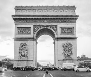 Cars on street by arc de triomphe against sky