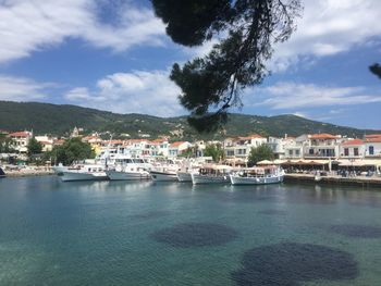 Houses at waterfront against cloudy sky