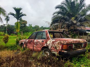 Abandoned car on field against sky