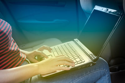 Midsection of woman using laptop while sitting in car