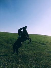 Man riding horse on land against sky