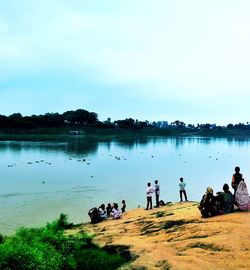 People swimming in lake against sky