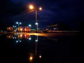 Illuminated cars on road against sky at night