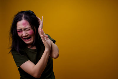 Portrait of young woman against yellow background