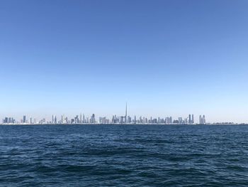 Scenic view of sea and buildings against clear blue sky