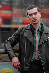 Portrait of young man standing by railing