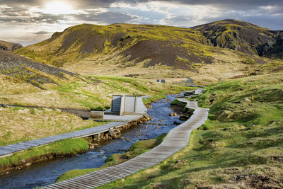 Wooden boardwalk and changing room by geothermal bath stream in hveragerdi