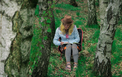 Woman drawing on book in forest