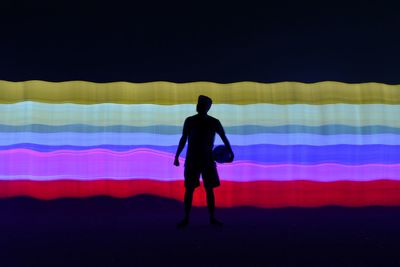 Digital composite image of silhouette man standing against colorful pattern