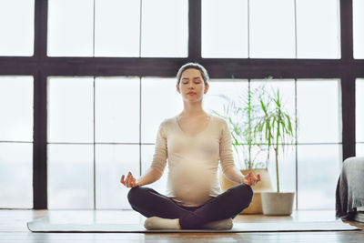 Young pregnant woman meditating at home