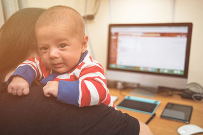 Close-up of portrait boy with mother sitting at home