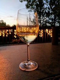 Close-up of wineglass on table against sky during sunset