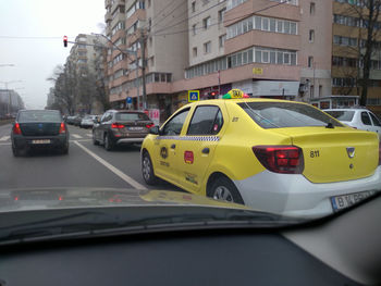 Traffic on road by buildings in city