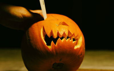 Cropped hand of person cutting pumpkin during halloween