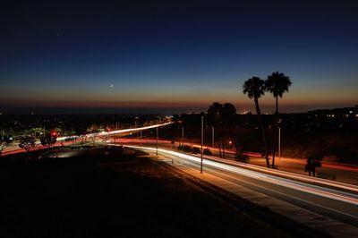 Light trails on road against clear sky at night