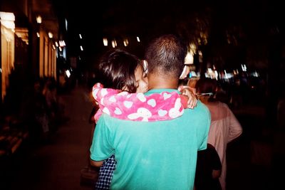 Rear view of couple kissing at night