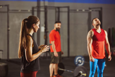 Woman using mobile phone while standing at gym