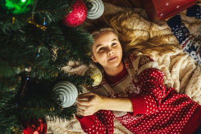 Portrait of woman lying by christmas tree